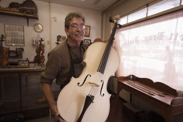 Mark Bluett with a cello at Bluett Bros. Violins in York, Pennsylvania