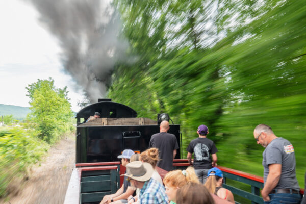 A steam powered train from the East Broad Top Railroad going through a wooded area.