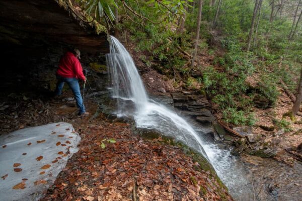 A man standing behind a waterfall in Sproul State Forest of PA
