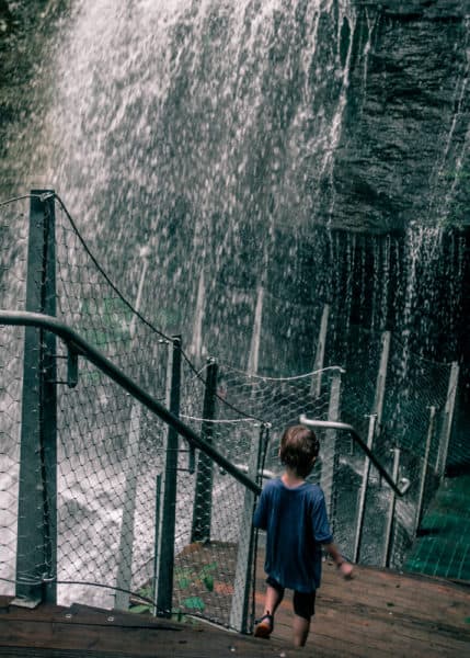 Child walking path behind waterfall at Buttermilk Falls in Indiana County PA