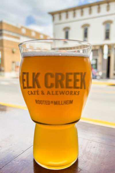 A glass of beer in front of a window at Elk Creek Aleworks in Millheim, PA.