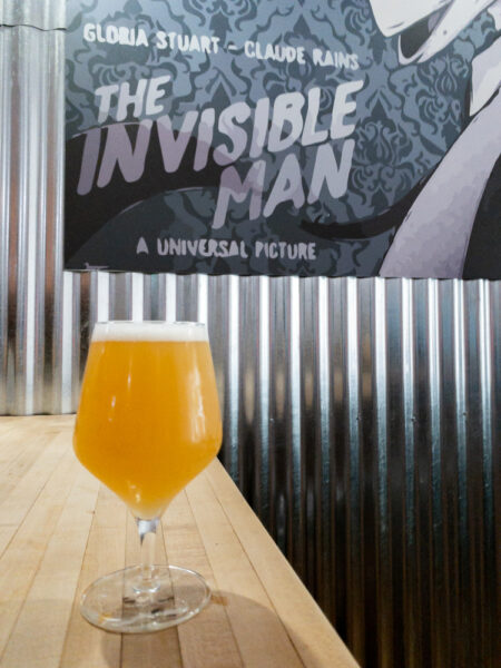 Invisible Man Brewing beer in front of a poster