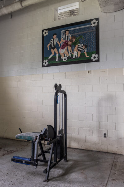 Weight equipment sits in front of an athletic mural inside the gymnasium at SCI Cresson