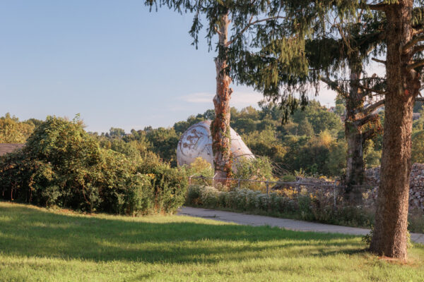 The Westinghouse Atom Smasher on the ground behind a lawn and trees