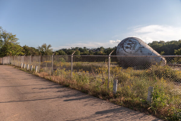 Westinghouse Atom Smasher lies in a field beyond a fence and next to a road