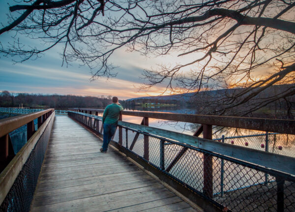 Man standing on the dam at Memorial Lake State Park in Lebanon County PA at sunset