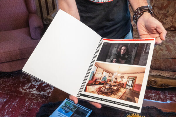 Man holding book of photos from "Silence of the Lambs" at Buffalo Bill's House in Perryopolis, PA