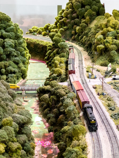 A train passing along a forested stream at the Western Pennsylvania Model Railroad Museum in Allegheny County PA