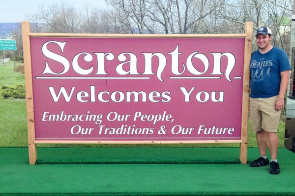 The author standing next to the Scranton Welcomes You Sign at the Steamtown Mall in Scranton Pennsylvania