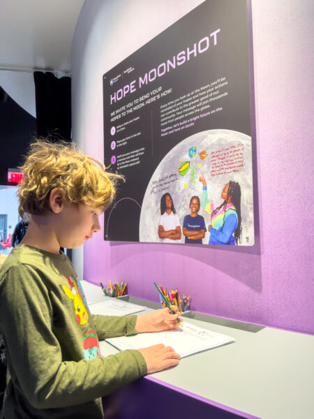 Boy writing a note at the Moonshot Museum in Pittsburgh, Pennsylvania