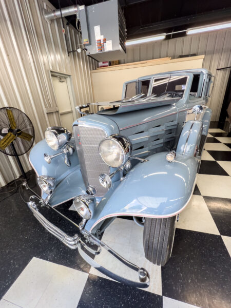A light blue historic Cadillac sits on a checkerboard floor at the Greenberg Cadillac Museum in Brookville Pennsylvania