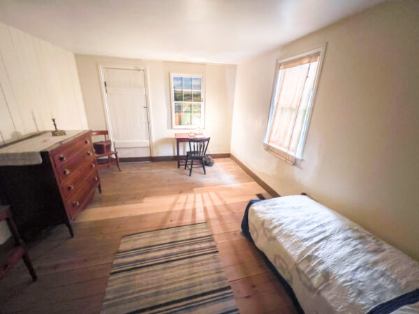 Downstairs bedroom with a bed and table in the John Brown House in Chambersburg Pennsylvania