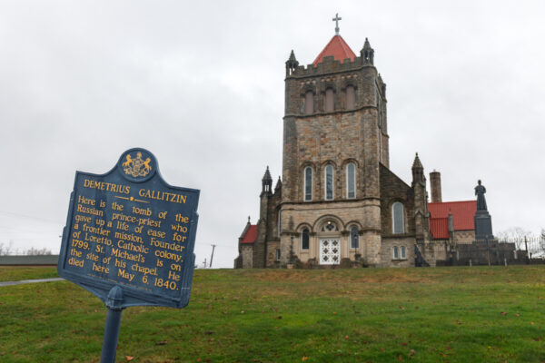 A wider look at the monument and basilica with a historic marker in front.