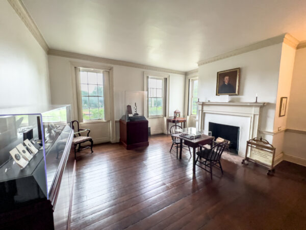 Parlor in the Joseph Priestley House with furniture in the middle of the room and display cases around the walls.