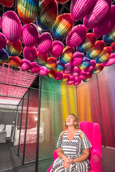 Woman sitting in a colorful art exhibit at WonderSpaces in Philadelphia PA