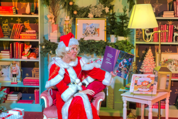 Mrs. Claus reading a book in a room at Tinseltown Holiday Spectacular in Philly.