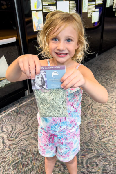 Child holding a bag of shredded money at the Money in Motion Exhibit at the Federal Reserve Bank of Philadelphia, PA