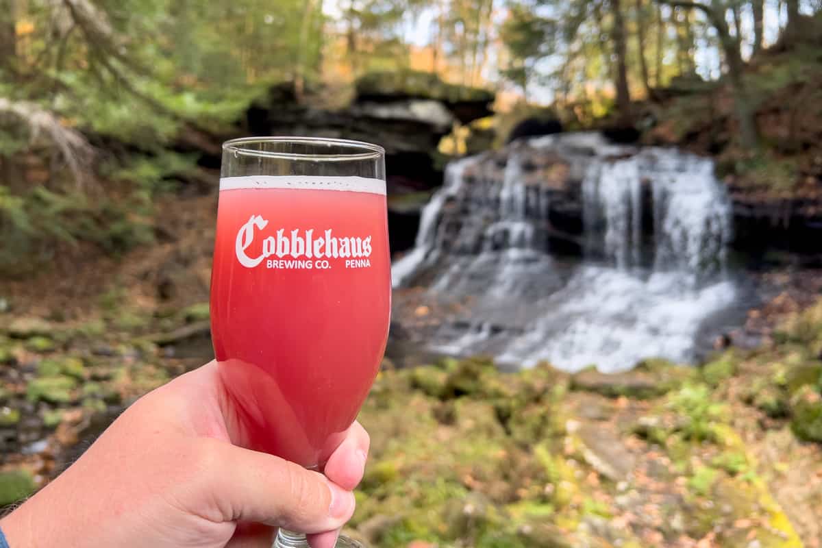 Holding a beer in front of a waterfall at Cobblehaus at the Falls in Mercer County PA