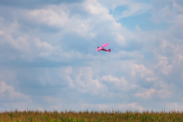 Pink plane flying in front of a blue sky above the Golden Age Air Museum in Berks County PA