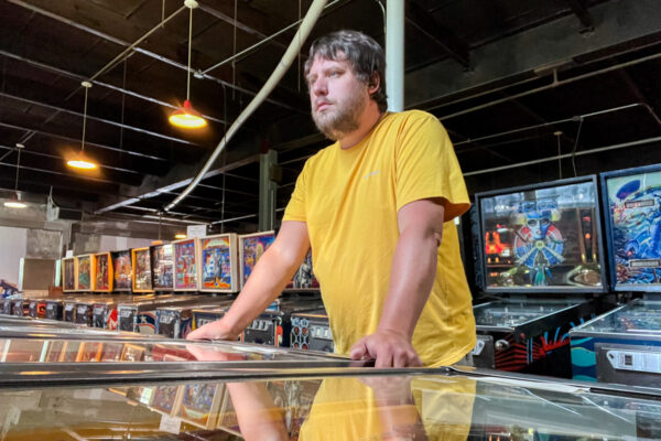 Man in a yellow shirt playing pinball at Pinball Perfection in Alleghany County PA