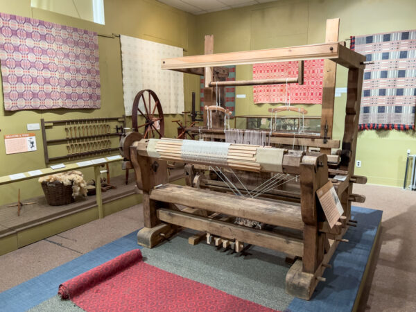 A historic loom sitting in a room with woven coverlet in the National Museum of the American Coverlet in Bedford, Pennsylvania