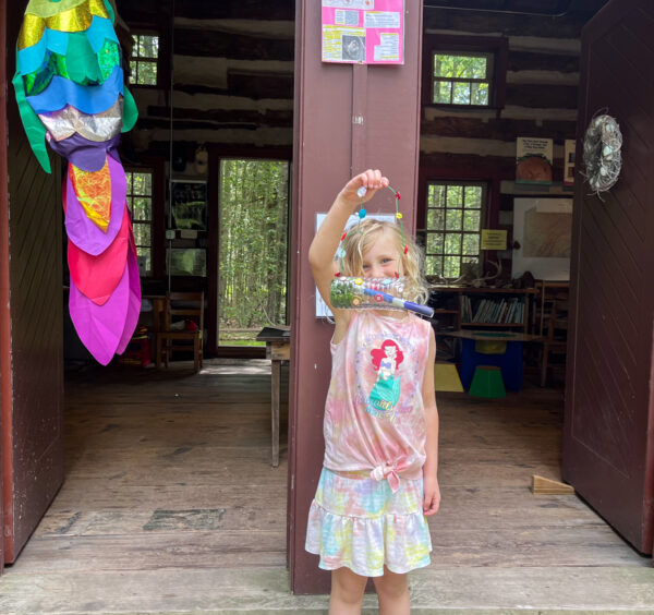 Child holding an art project outside the Conservancy Cabin in Eagles Mere, PA