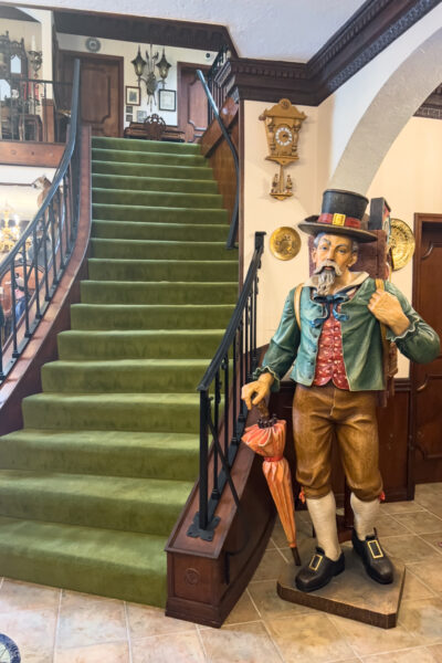 A green carpeted stairway next to a Bavarian man statue in the Bayernhof Museum near Pittsburgh PA