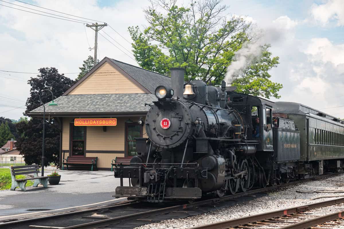 A steam engine sits next to a train station at the Everett Railroad in Hollidaysburg, PA