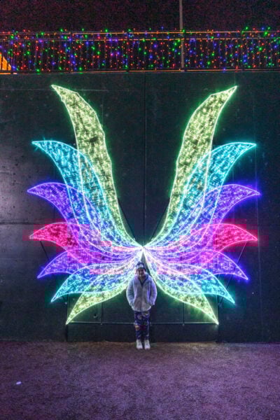 Girl standing in front of illuminated angel wings during Bright Nights in York PA