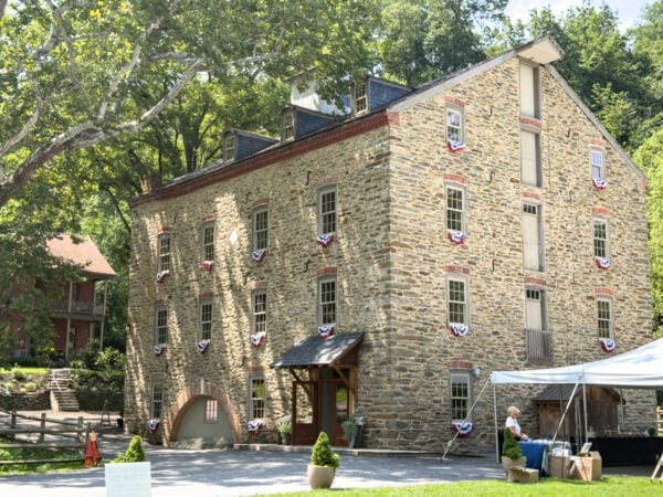 The historic stone Sickman's Mill in Lancaster County sitting amongst trees.