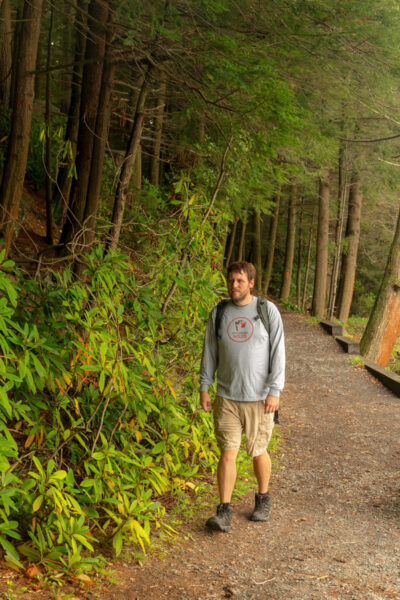 Man walking on a trail in a PA Wilds Shirt.