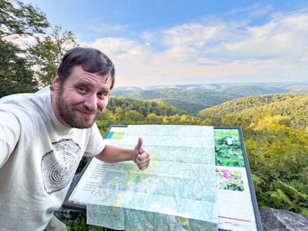 Man standing in front of an overlook and a signboard with a map in Potter County Pennsylvania